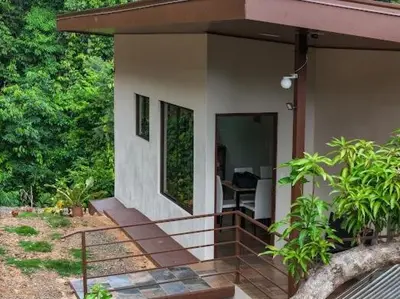 a small house with a porch and a desk at VILLA SANTA LUCÍA in front of the waterfall with a mountain view in Ceibo
