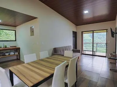 a dining room with a wooden table and white chairs at VILLA SANTA LUCÍA in front of the waterfall with a mountain view in Ceibo