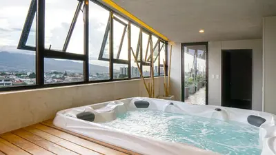 a large bath tub in a room with windows at Zen Urbano View of the Irazu Volcano con Jacuzzi and AC in Curridabat