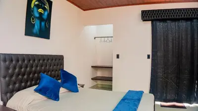 a bedroom with a bed with blue pillows at Toucan Villa Rio Cuarto in Río Cuarto