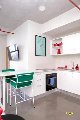 a kitchen with white cabinets and a green chair at Lovely space - awesome San Jose view from 26th fl in San José
