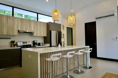 a kitchen with a counter with three stools at Casa La Junglita in Paraíso