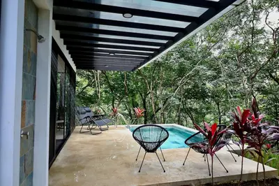 a patio with two chairs and a swimming pool at Casa La Junglita in Paraíso