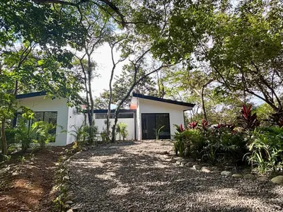 a white house in the middle of a forest at Casa La Junglita in Paraíso