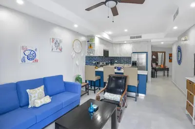 a living room with a blue couch and a kitchen at 2 Bedroom Oceanview Beachfront Condo Jaco Beach in Jacó