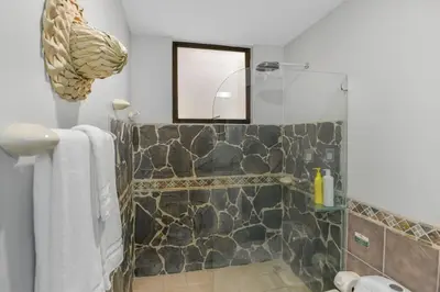 a bathroom with a stone shower with a mirror at 2 Bedroom Oceanview Beachfront Condo Jaco Beach in Jacó