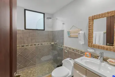 a bathroom with a toilet and a sink and a mirror at 2 Bedroom Oceanview Beachfront Condo Jaco Beach in Jacó