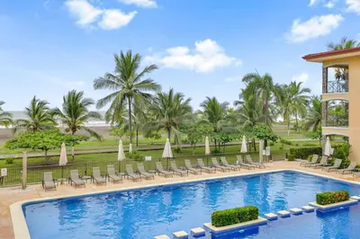 a pool at the resort with chairs and umbrellas at 2 Bedroom Oceanview Beachfront Condo Jaco Beach in Jacó