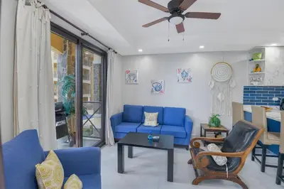 a living room with blue couches and a ceiling fan at 2 Bedroom Oceanview Beachfront Condo Jaco Beach in Jacó
