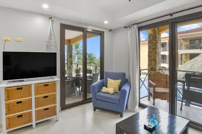 a living room with a tv and a blue chair at 2 Bedroom Oceanview Beachfront Condo Jaco Beach in Jacó