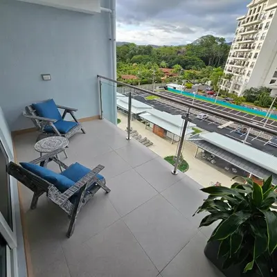a balcony with chairs and a view of a train at A short walk from the sea - 2 bedrooms - 2 beds - 2 bathrooms in Jacó