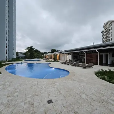 a large swimming pool with chairs and a building at A short walk from the sea - 2 bedrooms - 2 beds - 2 bathrooms in Jacó