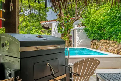 a grill and a chair next to a swimming pool at Tiburon Galano - Playa Carrillo in Carrillo