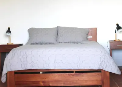 a bedroom with a wooden bed with a white comforter at Hotel El Arca, Jardín Botánico y Restaurante in Santa Bárbaraa