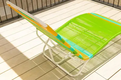 a green plastic chair sitting on a tile floor at Sunset view URBN Studio 16th floor in San José