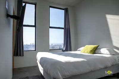 a bedroom with a large bed with windows at Sunset view URBN Studio 16th floor in San José