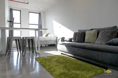 a living room with a couch and a table with a green rug at Sunset view URBN Studio 16th floor in San José