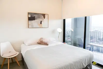 a bedroom with a white bed and a chair and a window at INSTAWORTHY CORNER VIEW 200Mbps in San José