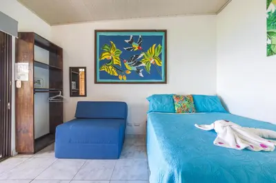 a bedroom with a blue bed and a blue chair at Hotel Villas de la Selva in Manuel Antonio