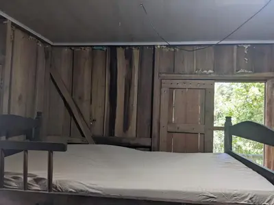 a bed in a room with a wooden wall at Avistamiento Fauna Flora Caribe in Puerto Limón