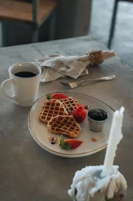 a plate with waffles and strawberries and a cup of coffee at Dar Lamia Boutique Hotel in Manuel Antonio