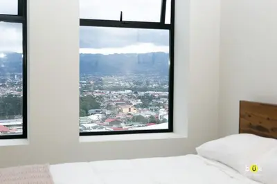 a bedroom with a window with a city view at Vistas a la montaña 1301 URBN in San José