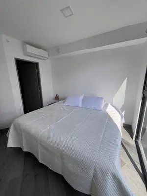 a white bedroom with a white bed with two pillows at Balcony Sunset in San José