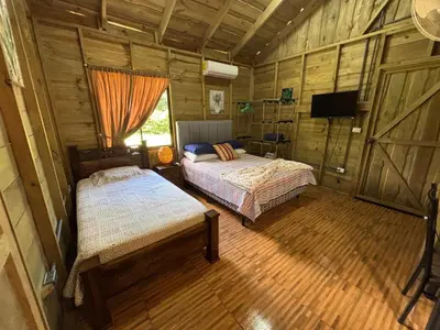 a bedroom with two beds in a wooden cabin at Cabaña Jacaranda #1, San Isidro, Pérez Zeledón in Roble