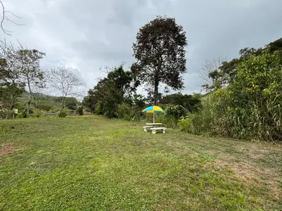 a picnic table with an umbrella in a field at Cabaña Jacaranda #1, San Isidro, Pérez Zeledón in Roble