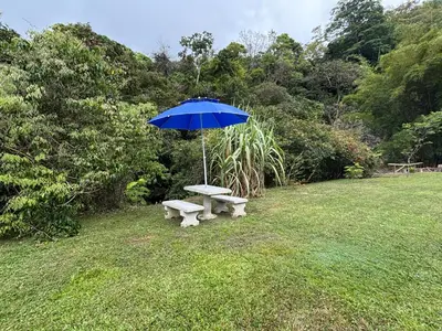 a picnic table with an umbrella in a field at Cabaña Jacaranda #1, San Isidro, Pérez Zeledón in Roble