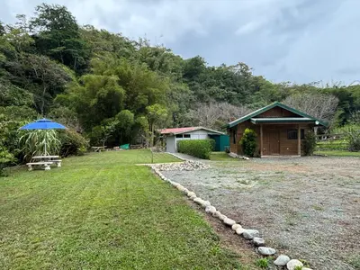 a yard with a house and a blue umbrella at Cabaña Jacaranda #1, San Isidro, Pérez Zeledón in Roble