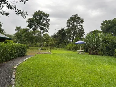 a park with a bench and an umbrella in the grass at Cabaña Jacaranda #2, junto al río, San Isidro, Pérez Zeledón in Roble
