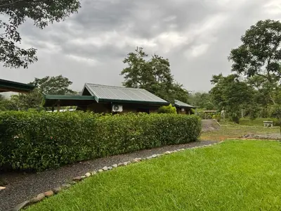a house with a green roof and some bushes at Cabaña Jacaranda #2, junto al río, San Isidro, Pérez Zeledón in Roble