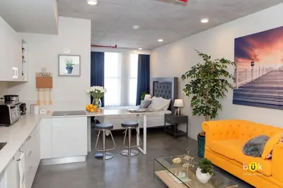 a kitchen and living room with a yellow couch at Cozy New Studio Excellent Location in San José