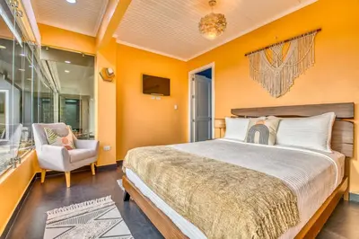 a bedroom with orange walls and a bed and a chair at Castillo Colonial Nosara - by Pura Villas in Nosara