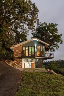 a house on a hill with people sitting on a balcony at CasaYvyra 'i in Sierra