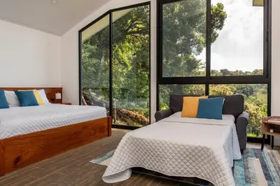 two beds in a room with large windows at CasaYvyra 'i in Sierra