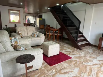 a living room with two couches and a staircase at Casa Tucán Turrialba in Turrialba
