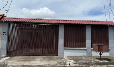 a building with a gate and a bench in front of it at Casa Tucán Turrialba in Turrialba