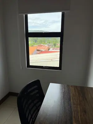 a table and a chair in a room with a window at Casa Tucán Turrialba in Turrialba