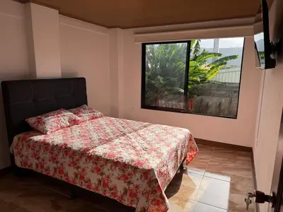 a bedroom with a bed and a large window at Casa Tucán Turrialba in Turrialba