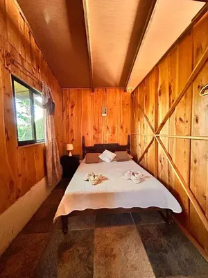 a bedroom with a bed with wooden walls and a window at Ecos del Poás junto a la piscina in Alajuela City