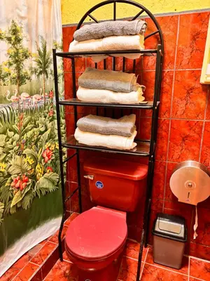 a towel rack with a red toilet in a bathroom at Sol y Mar Condominio don Roberto in Jacó