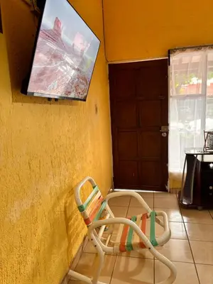 a chair sitting in the corner of a room with a tv at Sol y Mar Condominio don Roberto in Jacó