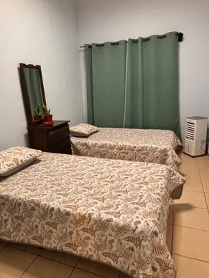 two beds in a room with a green curtain at Sol y Mar Condominio don Roberto in Jacó