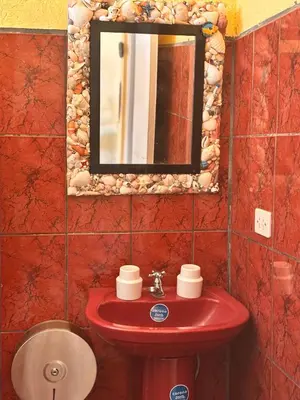 a bathroom with a red sink and a mirror at Sol y Mar Condominio don Roberto in Jacó