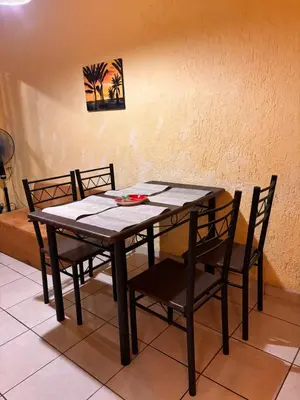 a wooden table and chairs with a table and a picture on the wall at Sol y Mar Condominio don Roberto in Jacó