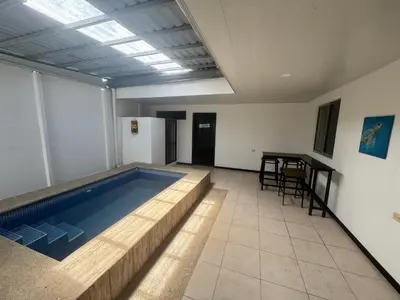a large swimming pool in a room with a table at Casa Bela in Parrita