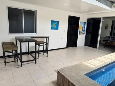 a living room with a table and chairs next to a pool at Casa Bela in Parrita