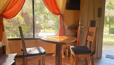 a table and chairs in a room with a window at Mei Tai Cacao Lodge in Bijagua
